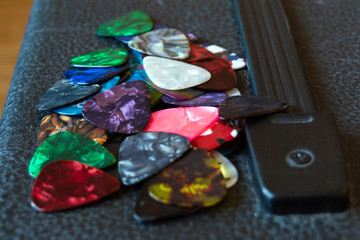 a lot of guitar picks of different colors, lie in random order on a guitar amp