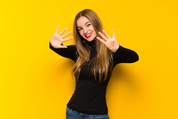 Young pretty woman over yellow background counting nine with fingers