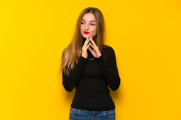 Young pretty woman over yellow background scheming something