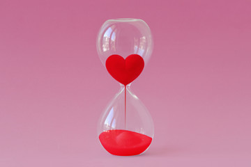 Red heart flowing in hourglass on pink background - Time for love concept