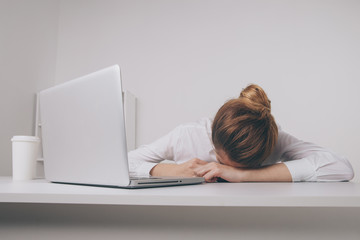 Overworked and tired sleeping over a laptop in a desk at work in her office