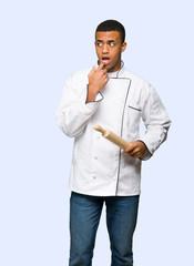 Young afro american chef man having doubts while looking up on isolated background