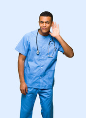 Surgeon doctor man listening to something by putting hand on the ear on isolated background