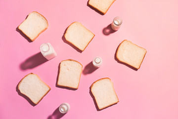 A slice of rye bread and milk on a  pink background