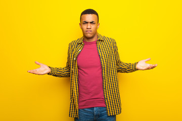 Young afro american man on yellow background unhappy and frustrated with something because not understand something