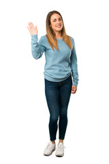 Obraz premium Full body of Blonde woman with blue shirt saluting with hand with happy expression on white background