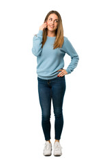 Full body of Blonde woman with blue shirt keeping a conversation with the mobile phone on white background