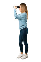 Full body of Blonde woman with blue shirt and looking in the distance with binoculars on white background