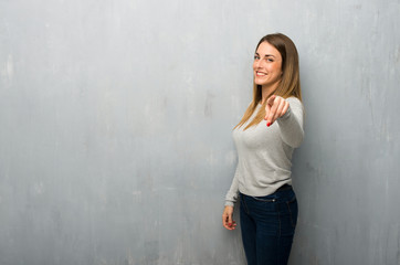 Fototapeta premium Young woman on textured wall points finger at you with a confident expression