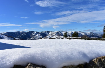 Winter landscape with snowy mountains and field with stone wall covered with snow. Piornedo Village, Ancares Region, Lugo, Spain.