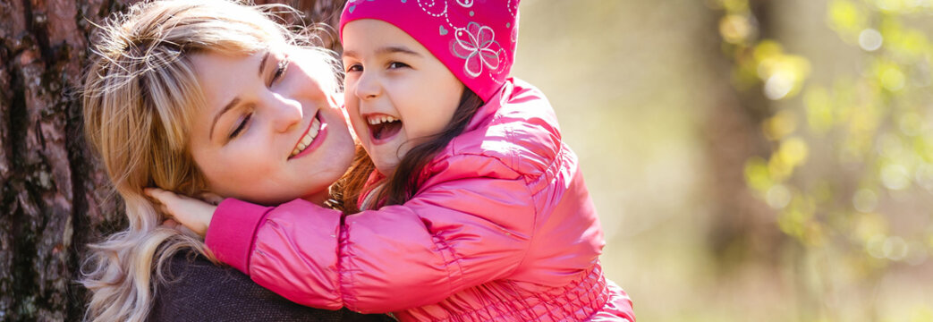 Cute young daughter on a piggy back ride with her mother.