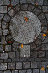 Scandinavian manhole in its urban surrounding.  Hidden beauty in design, texture, colors, shape and pattern of a sewer cover 