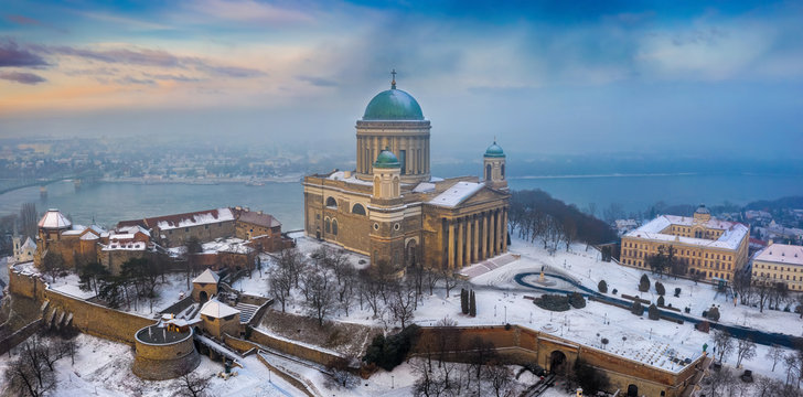 Esztergom, Hungary - Aerial panoramic view of the beautiful snowy Basilica of Esztergom with Slovakia at the background on a foggy winter morning