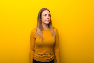 Young woman on yellow background looking up with serious face