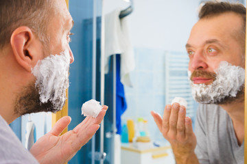 Guy shaving his beard in bathroom