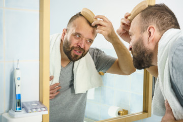 Man using comb in bathroom