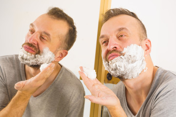 Guy shaving his beard in bathroom