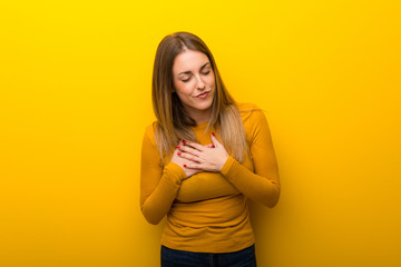 Obraz premium Young woman on yellow background having a pain in the heart