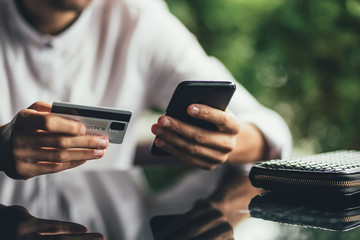 Young business man using credit card shopping online in coffee shop cafe. close up