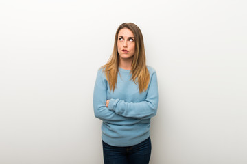 Blonde woman on isolated white background with confuse face expression while bites lip