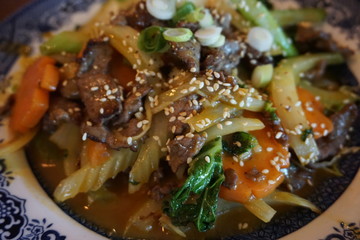 Stir fried vegetable noodles with beans carrot shrimp pork egg sausage onion beef chillies on white plate Vietnamese traditional food asian cuisine 