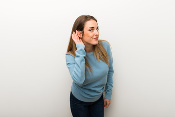 Fototapeta premium Blonde woman on isolated white background listening to something by putting hand on the ear