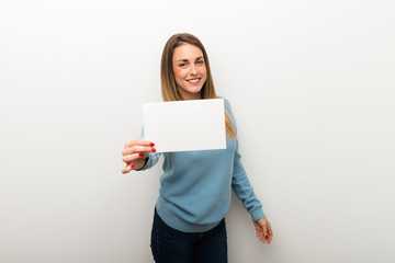 Fototapeta premium Blonde woman on isolated white background holding an empty white placard