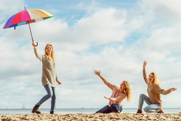 Women holding umbrella having fun with friends