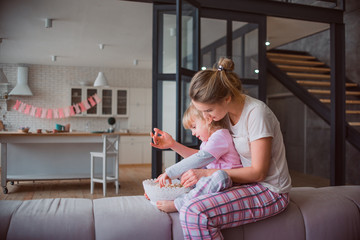 Mom and daughter in pajamas eating popcorn