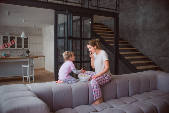 Mom And Daughter In Pajamas Eating Popcorn