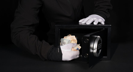 thief stealing valuables from safe at crime scene