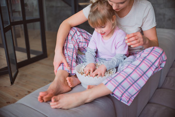 Mom and daughter in pajamas eating popcorn