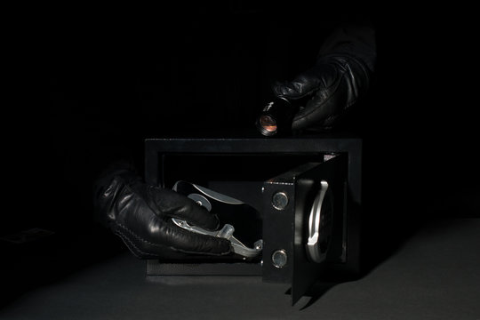 a thief stealing digital data from black gloves safes