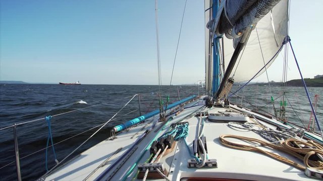 View of the yacht nose (with marine tackle) that is sailing along the Peter the Great Gulf taking part in regatta. Vladivostok, Russia. Beautiful blue sea of Japan