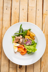 tuna salad, with tomatoes, eggs, red onion and green beans. Wooden background