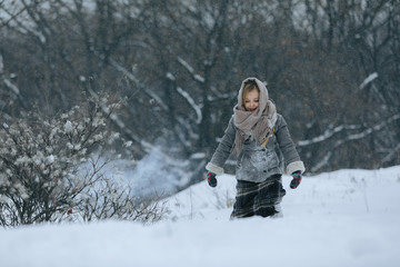Fototapeta na wymiar cute little child girl in the forest in winter. snowing and snowstorm