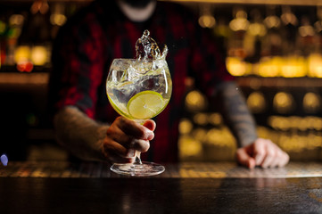 Mixologist holding a glass of fresh sour and sweet citrus cocktail