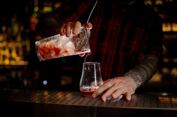 Bartender pouring fresh and tasty bittersweet red cocktail