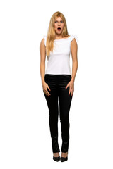 Young blonde woman with surprise and shocked facial expression over isolated white background