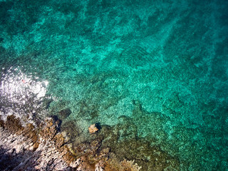 Naklejka na ściany i meble top view of rocky shore crystal clear Adriatic Sea, drone shot