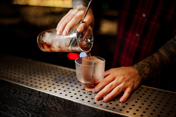 Barman pouring fresh and strong whiskey cocktail