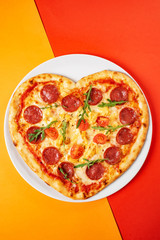 Heart shaped pizza with meat and vegetables. Food concept of romantic love for Valentines Day.