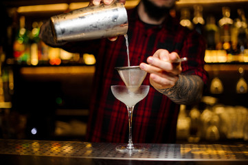 Fototapeta na wymiar Bartender pouring fresh alcoholic drink into an elegant glass