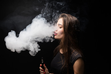 Young woman smoking electronic cigarette against a black background
