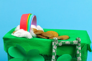 DIY leprechaun trap with gold coins, rainbow and green ladder St Patricks Day background.