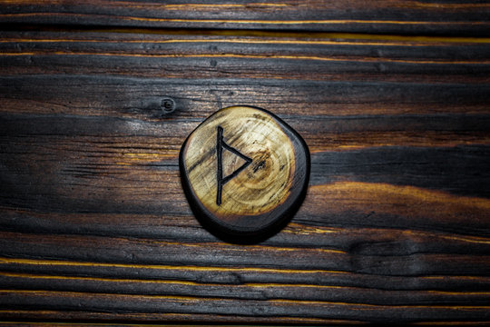 Rune Thurisaz (Thurs) carved from wood on a wooden background - Elder Futhark