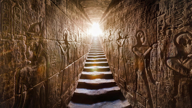 EGYPT Edfu, Aswan temple, completed by Ramses II (-1200). Passage flanked by two glowing walls full of Egyptian hieroglyphs, illuminated by a warm orange backlight from a door at the