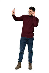 Naklejka premium Full-length shot of Handsome man with glasses making a selfie on isolated white background