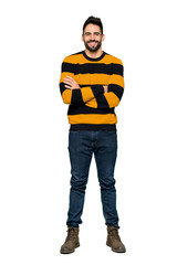 Naklejka premium Full-length shot of Handsome man with striped sweater keeping the arms crossed in frontal position on isolated white background