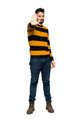 Full-length shot of Handsome man with striped sweater making stop gesture denying a situation that thinks wrong on isolated white background